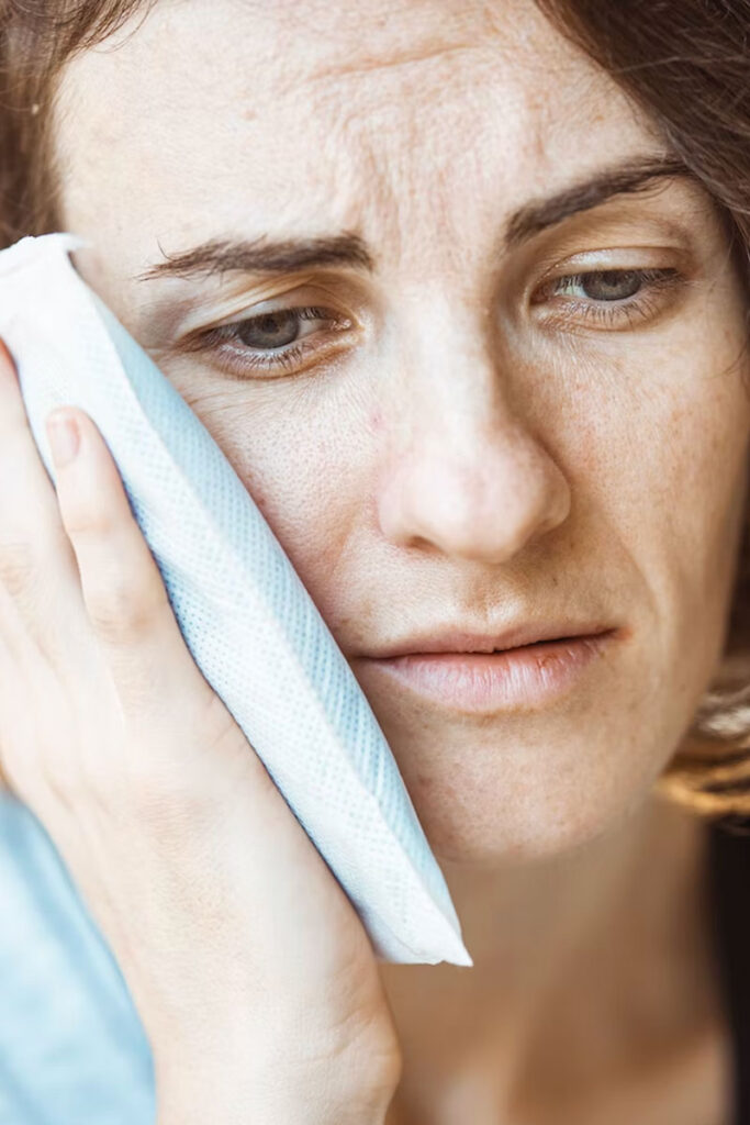 patient with a dental emergency clutching her mouth